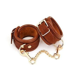 Vintage brown leather sex wrist cuffs for arm play with adjustable straps and metal chain attachment.