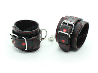 What you see is an image of Leather Thigh Ankle and Wrist Cuffs for Sex Slave Punishment in black and red with heart-shaped cutouts and metal chain.