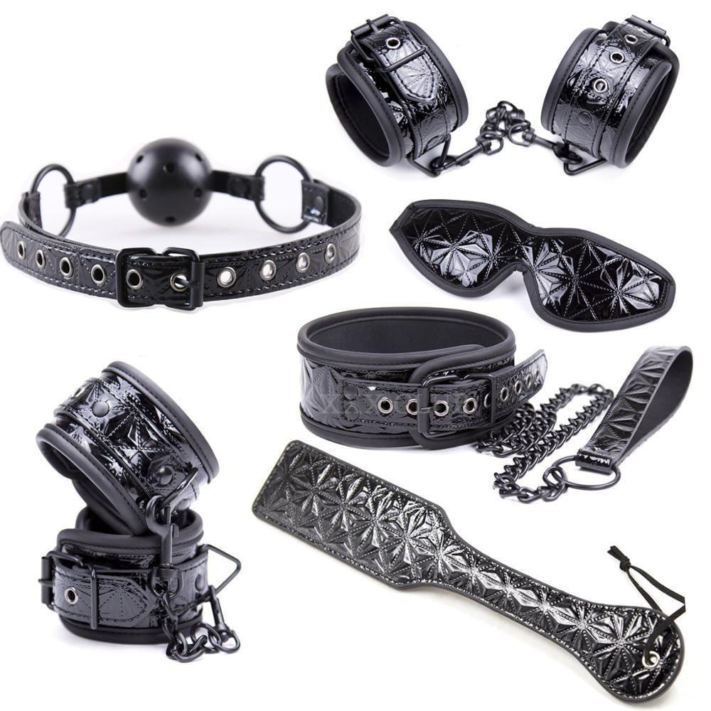 Pictured here is an image of Ultimate Luxury BDSM Leather Body Strap and Restraint Kit showcasing handcuffs, collar with leash, ankle cuffs, gag, and paddle.