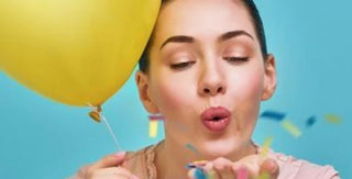 woman blowing confetti with a yellow balloon